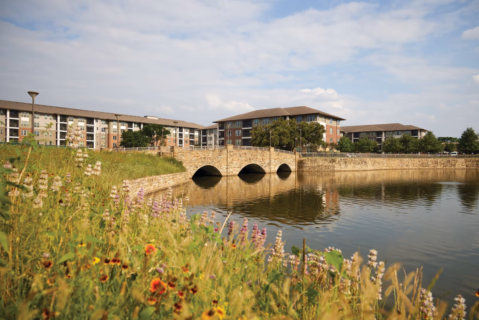 Exterior view of Continuing Care at Eagles Trace with a lakeside stone bridge and buildings