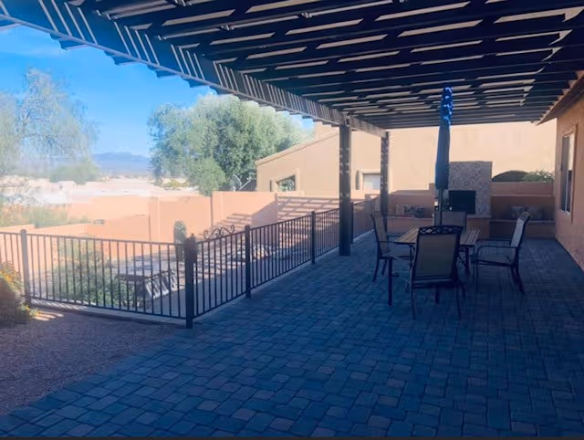 Covered outdoor patio with seating and railing overlooking a desert landscape.