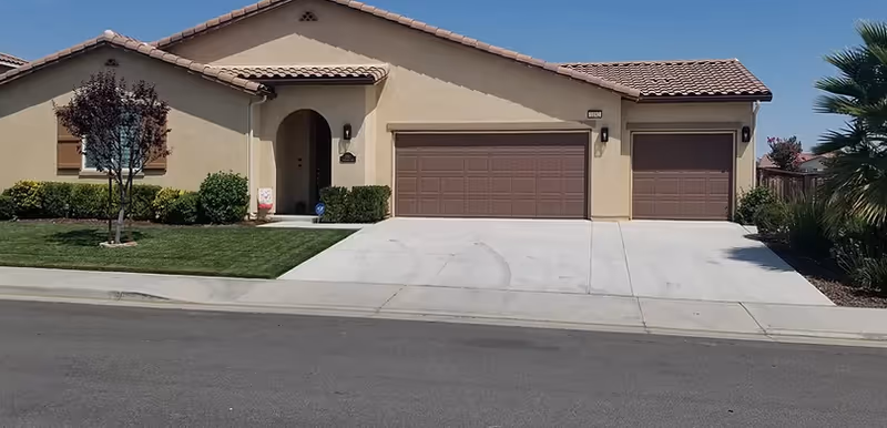Front view of a single-story beige senior living home with a three-car garage.