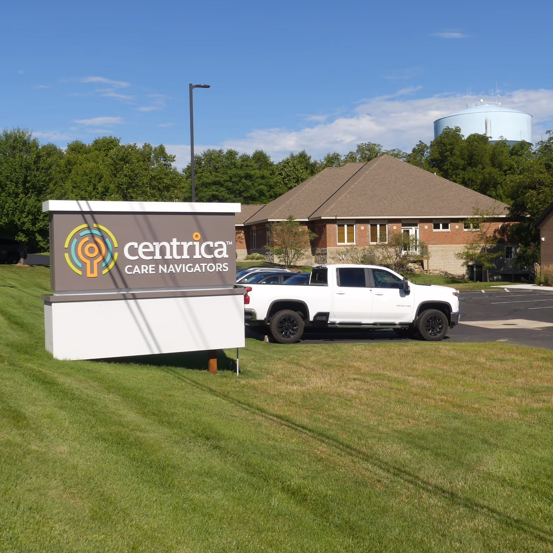 Exterior view of Centrica Care Navigators sign, white pickup, and brick facility building.