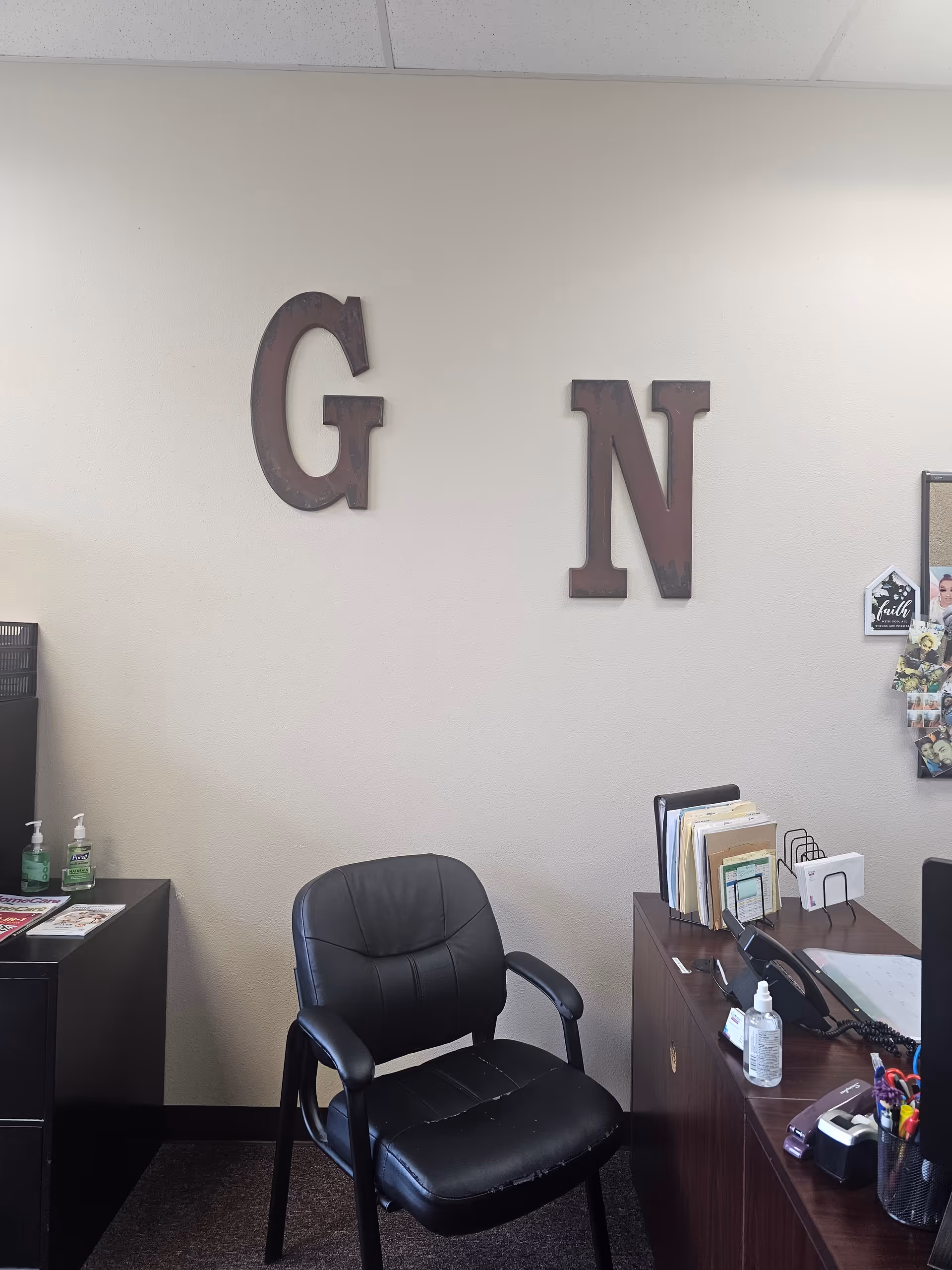 Reception desk area with black chair and large G and N letters on wall.