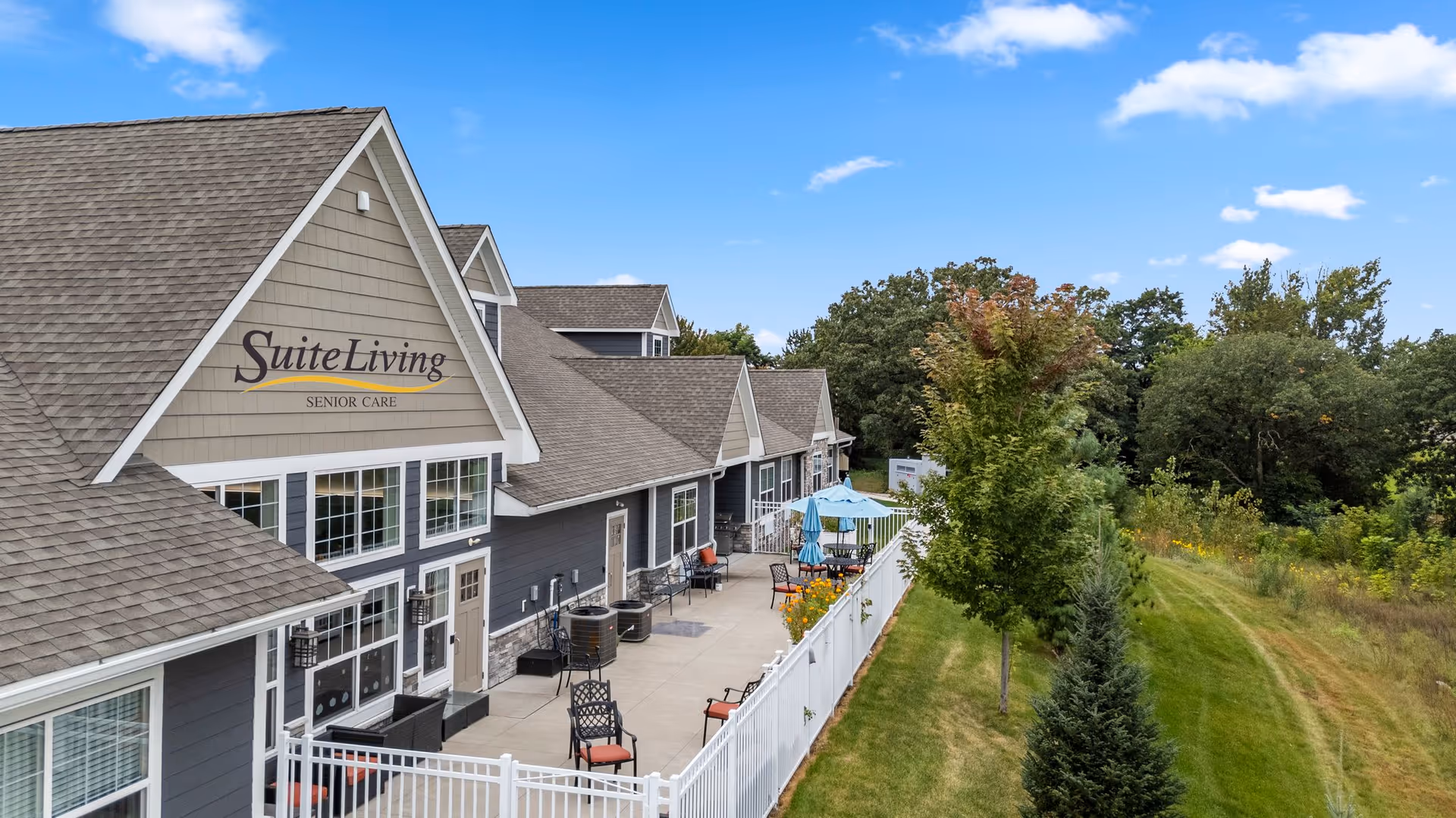 Exterior view of Suite Living Senior Care with a patio and outdoor seating along the building.