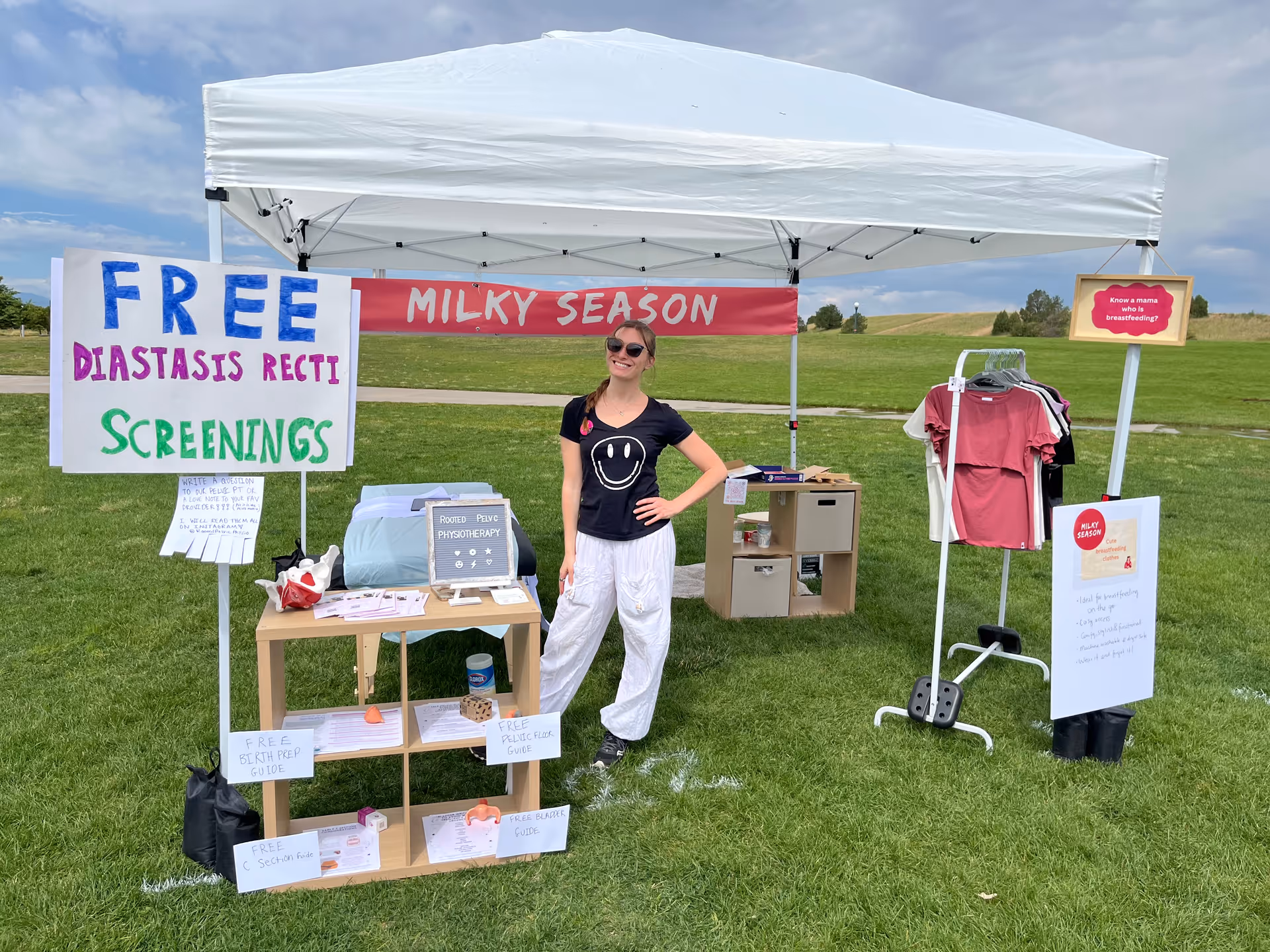 Outdoor tent booth offering free diastasis recti screenings with a smiling presenter.