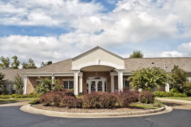 Front view of Paragon of Madisonville senior living facility with circular driveway and landscaped entrance.
