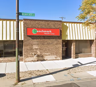 Brick storefront with Benchmark Health Corp sign on the sidewalk along Milwaukee Ave.