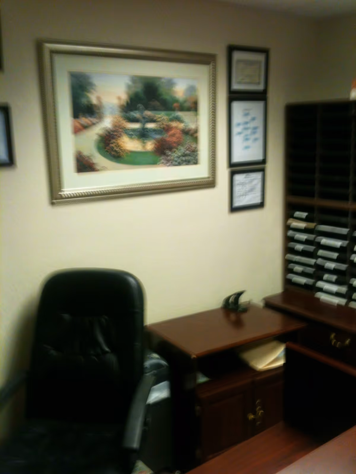 Small office space featuring a desk, chair, and framed wall artwork.