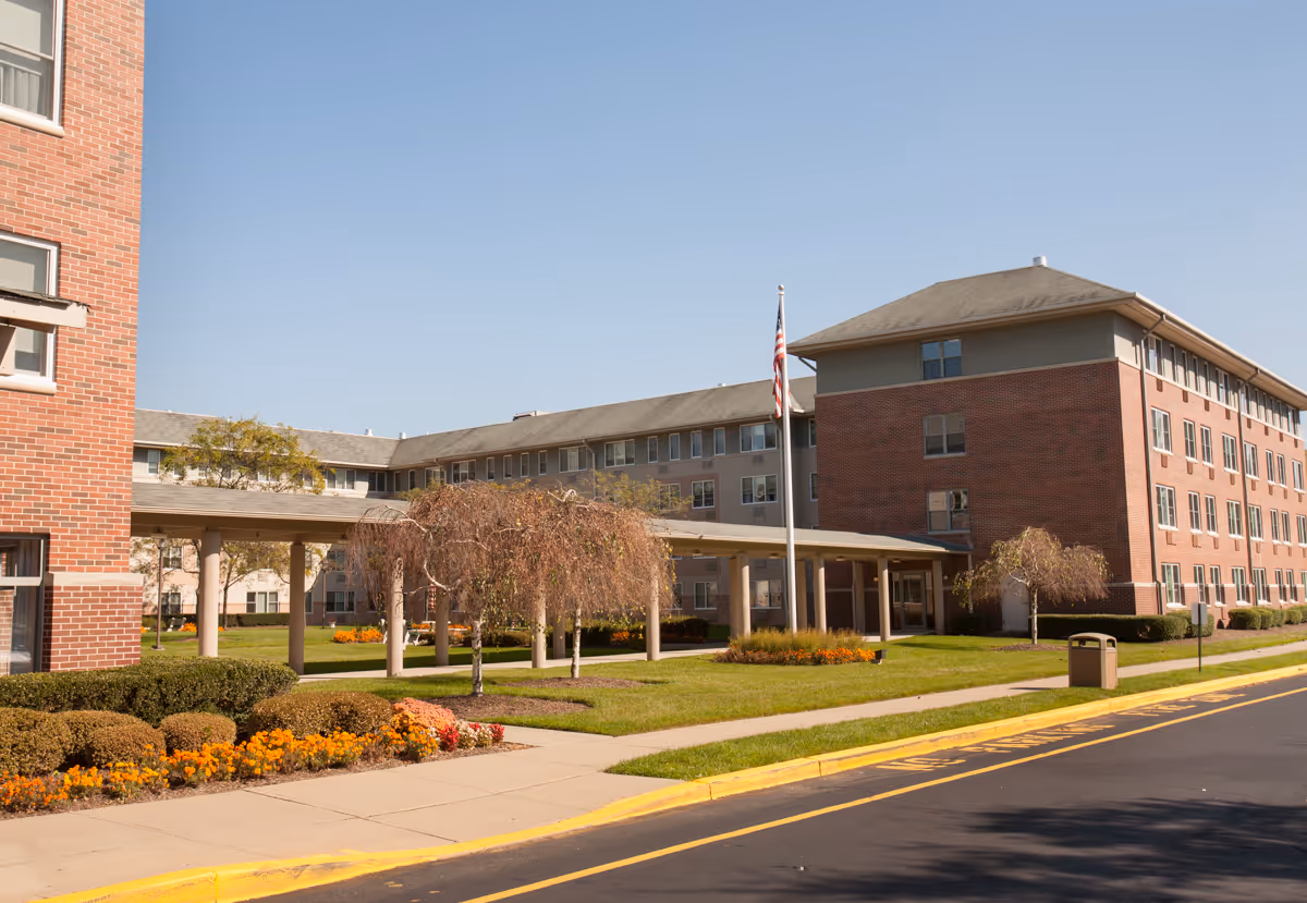 Exterior view of Siena Village at Wayne with brick building, flagpole, and landscaped entrance.