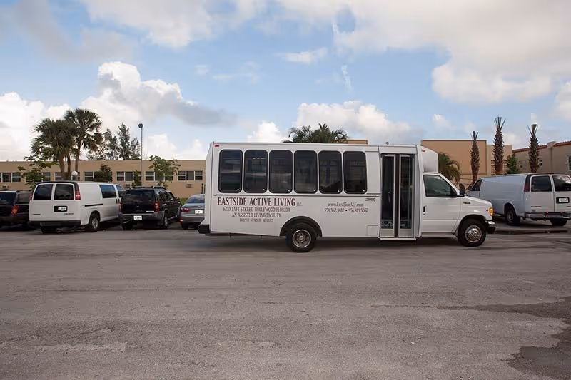 White shuttle bus labeled Eastside Active Living parked in a lot by a building