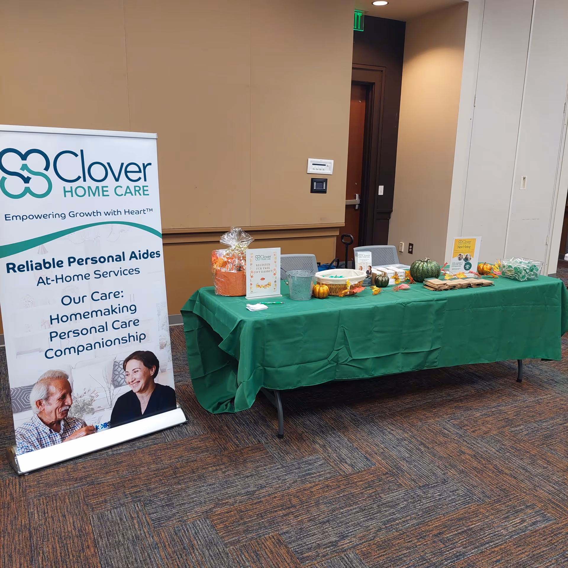 Indoor conference area with Clover Home Care Greenville banner and promotional table.