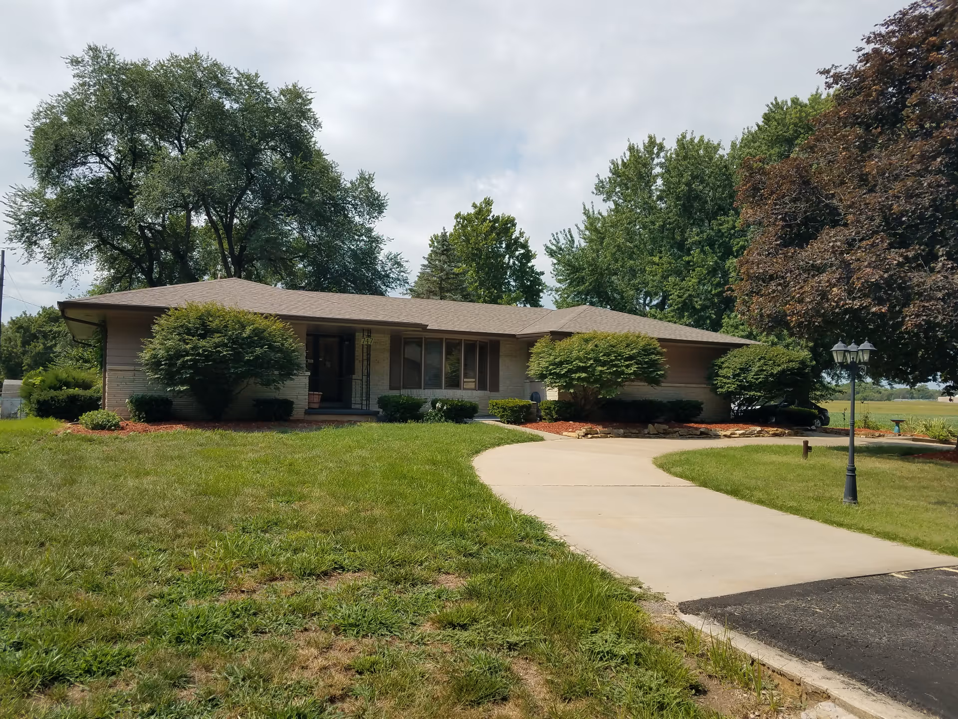 Single-story senior living facility with a curved driveway, well-kept lawn and trees.
