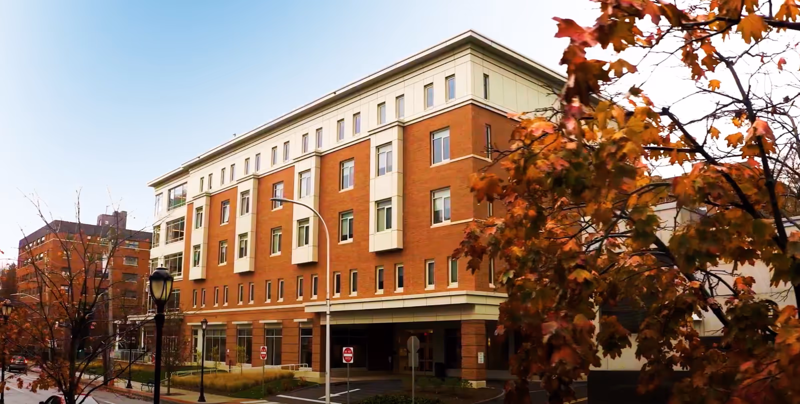 Exterior view of a brick senior living facility with trees and a street in front.