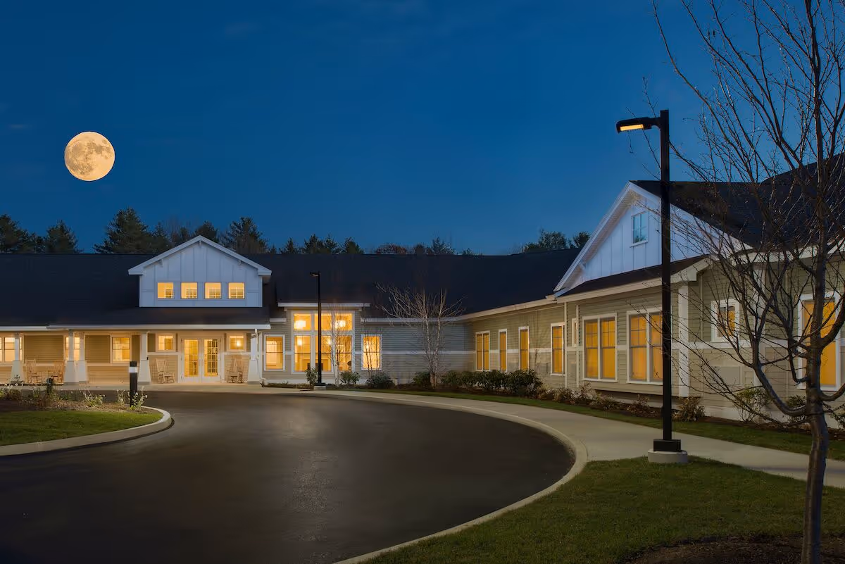 Exterior view of Avita of Wells facility at dusk with a curved driveway and lit windows.
