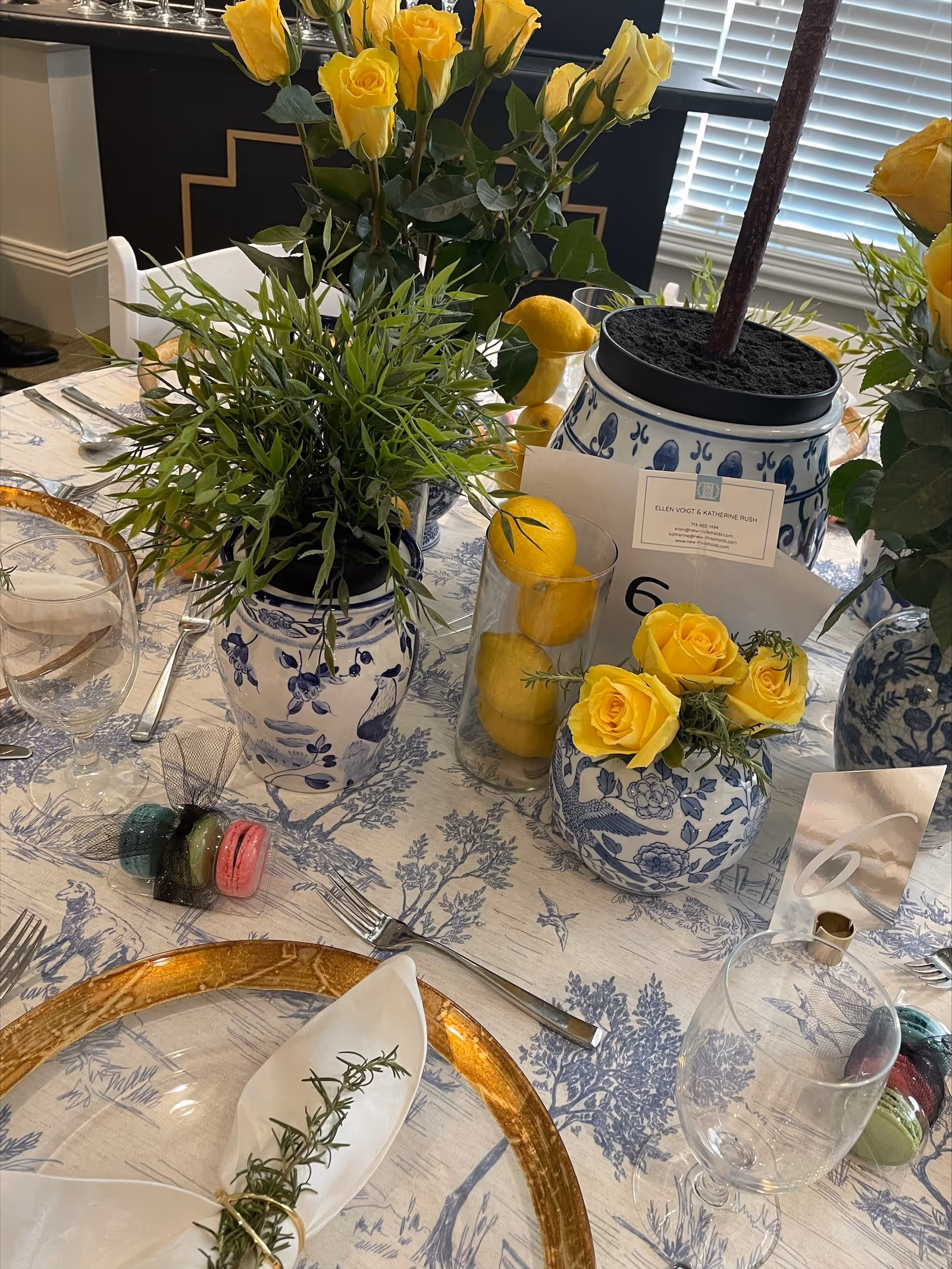 Elegant table setting with blue floral china, yellow roses, and lemons indoors.