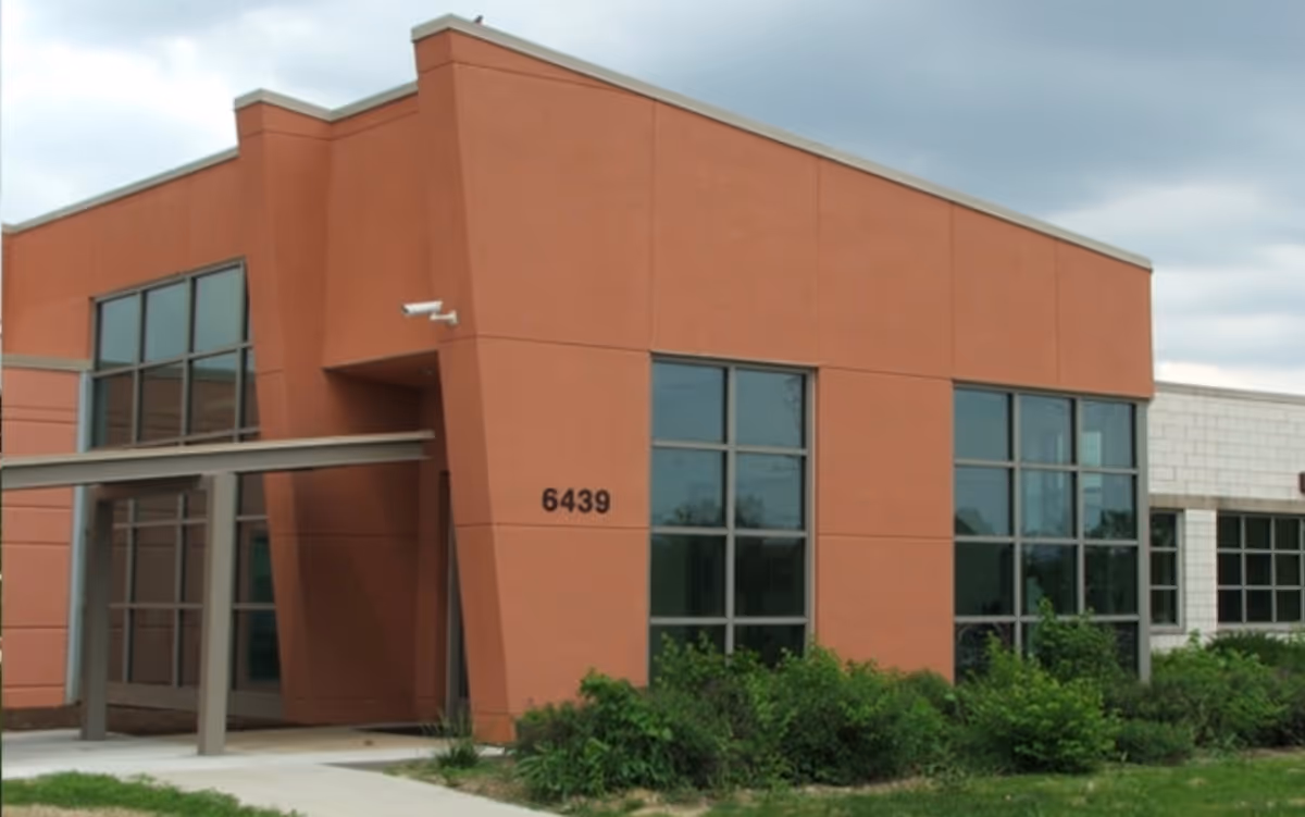 Orange-toned facility exterior with large windows and a covered entrance.