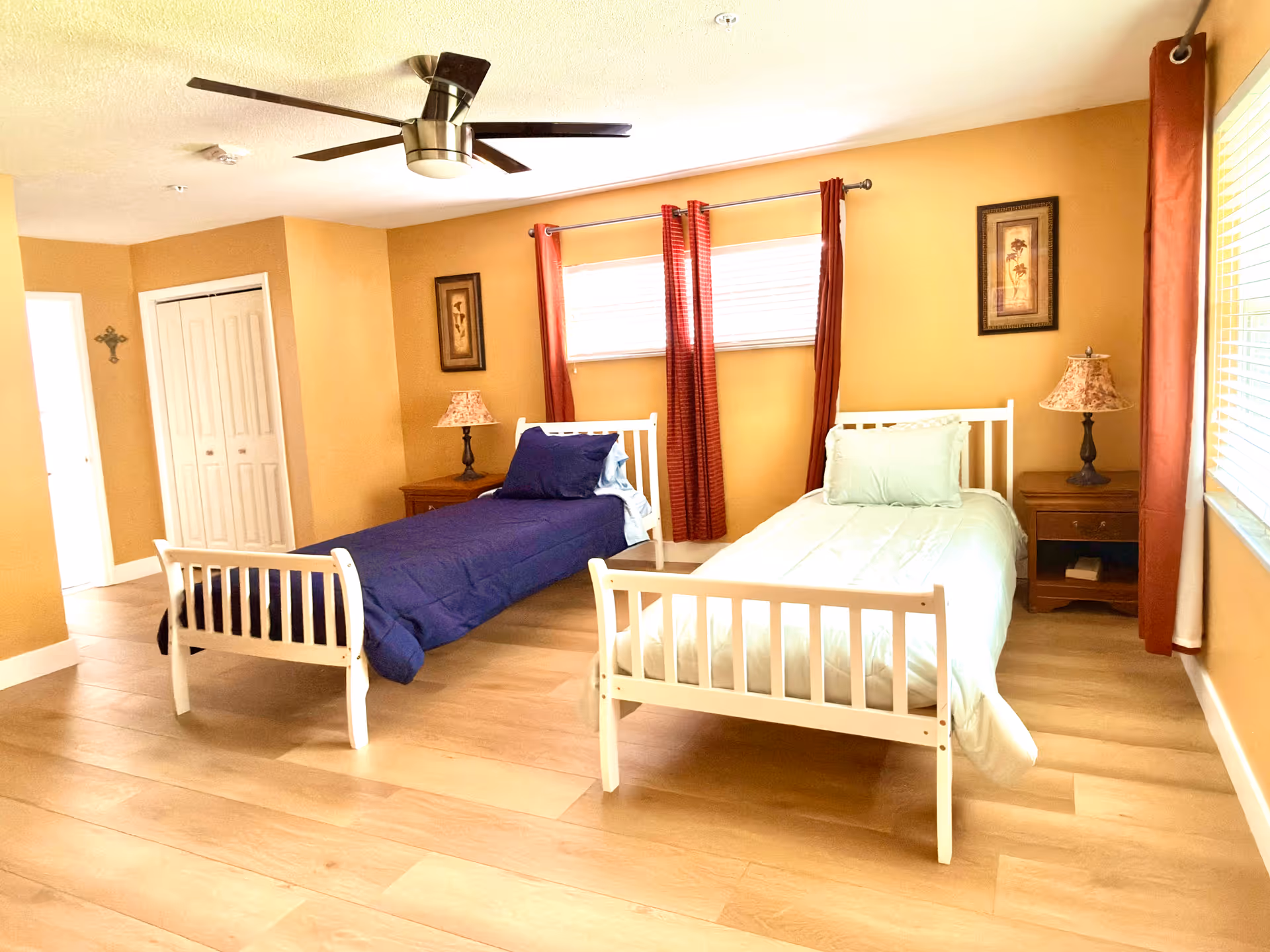 Two white twin beds with nightstands in a warmly lit shared bedroom.