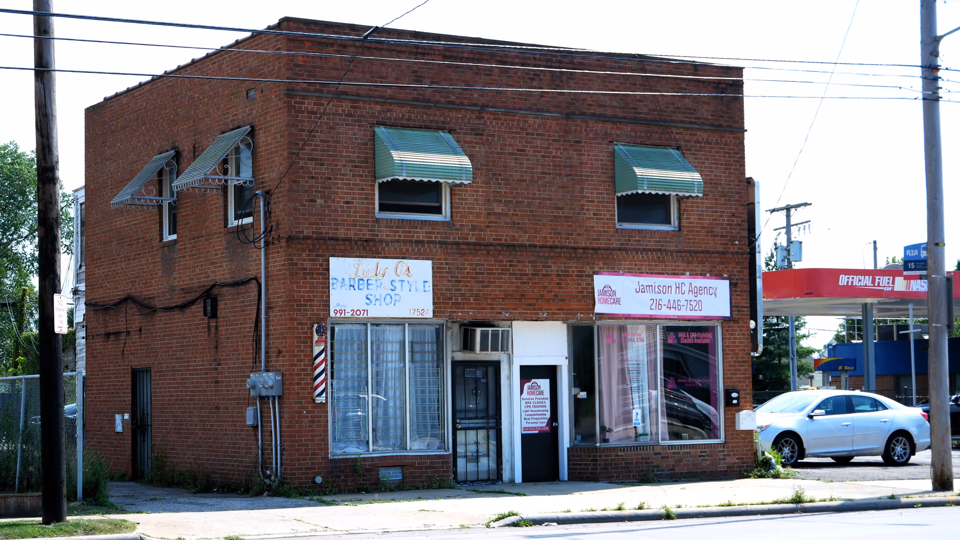 Brick, two-story storefront building with Jamison HC Agency sign and adjacent barber shop.