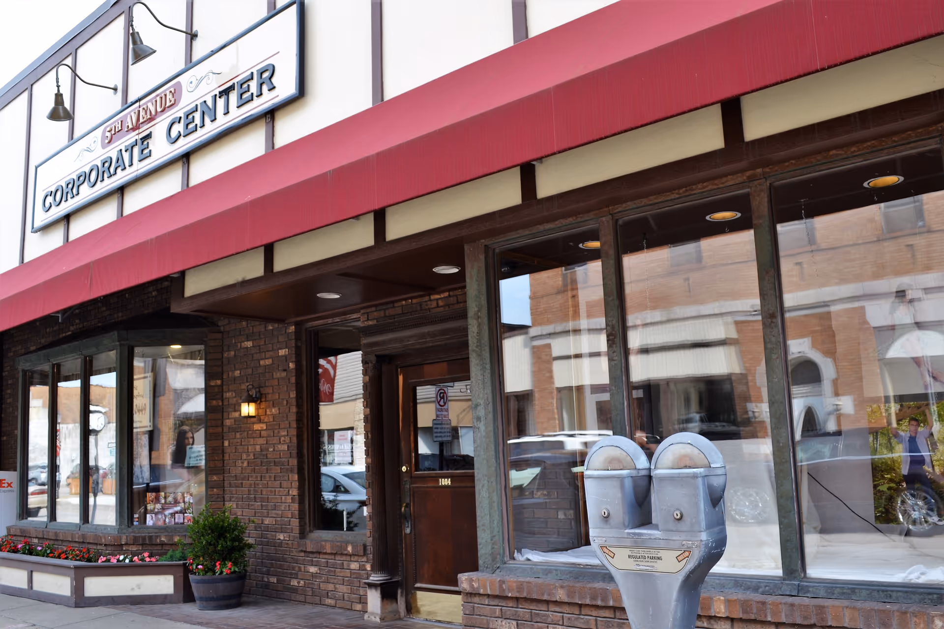 Brick storefront with large windows, a red awning, and a front entrance.