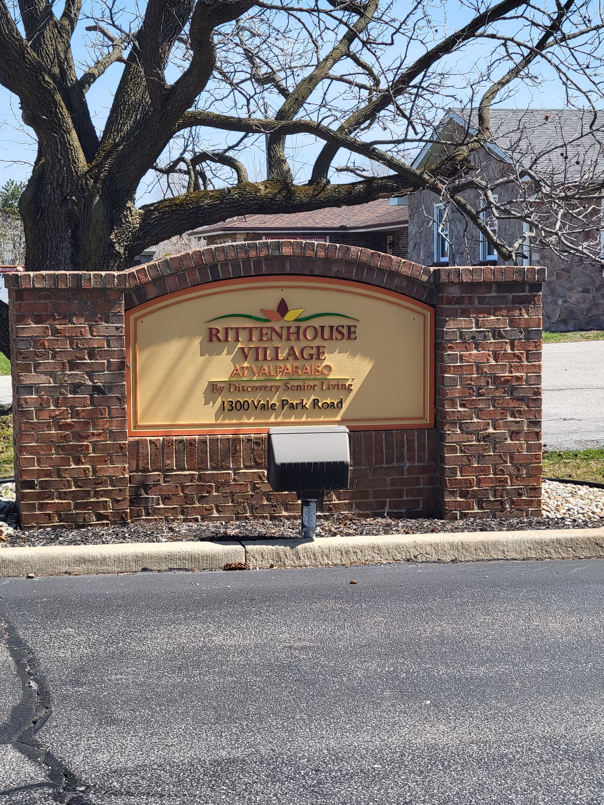 Brick entrance sign for Rittenhouse Village Valparaiso in front of a building.