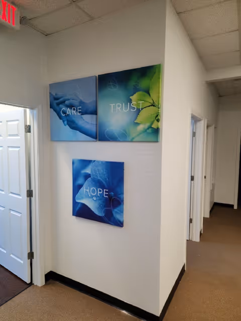 Interior hallway with wall art displaying CARE, TRUST, and HOPE in a senior facility.