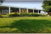 Single-story facility with a white veranda, columns, and a manicured lawn.