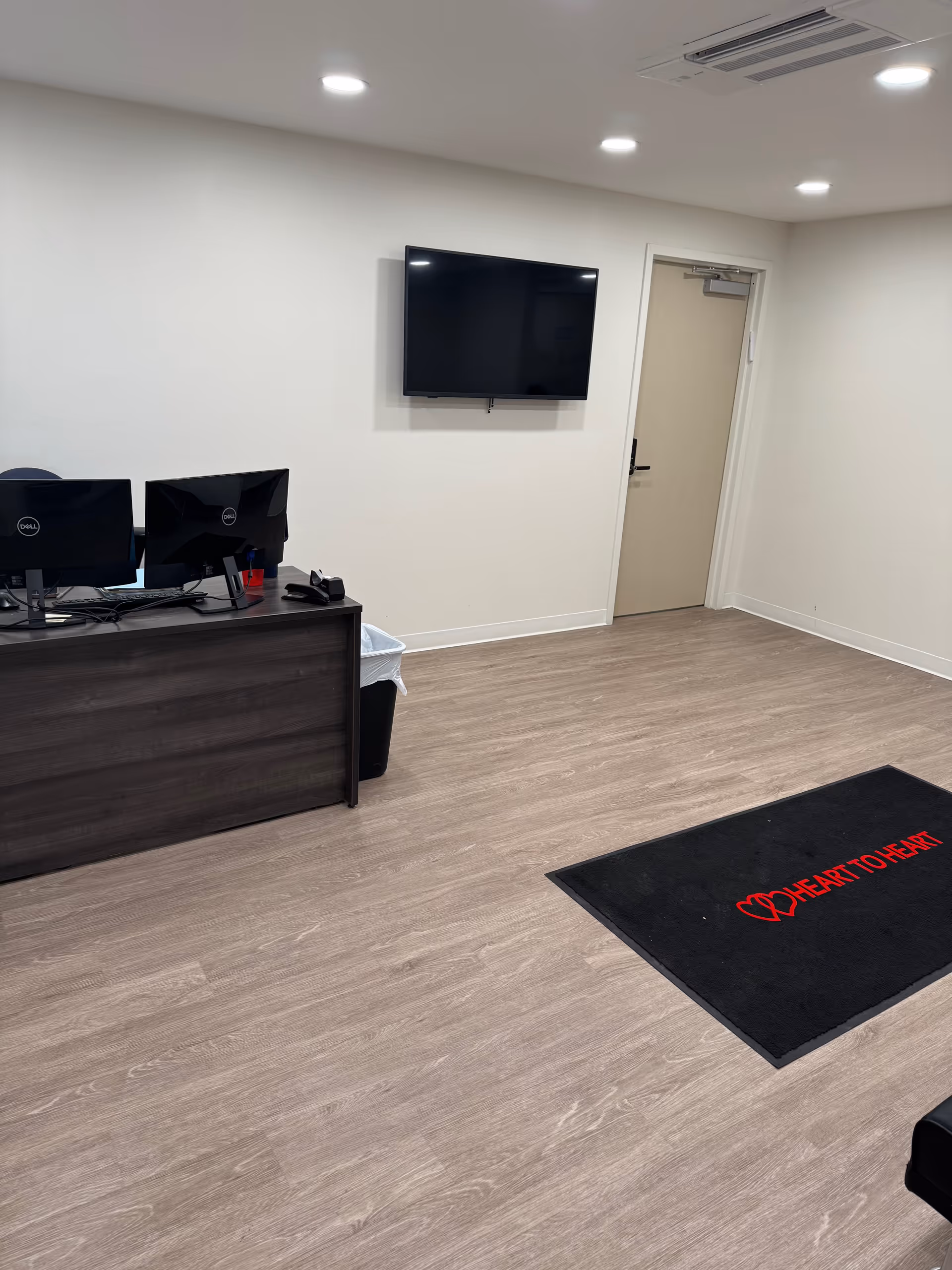 Reception desk with computers, wall-mounted TV, and doorway in a clean interior.