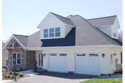Front view of Warm Hearth Village senior living facility with three garage doors and stone accents.