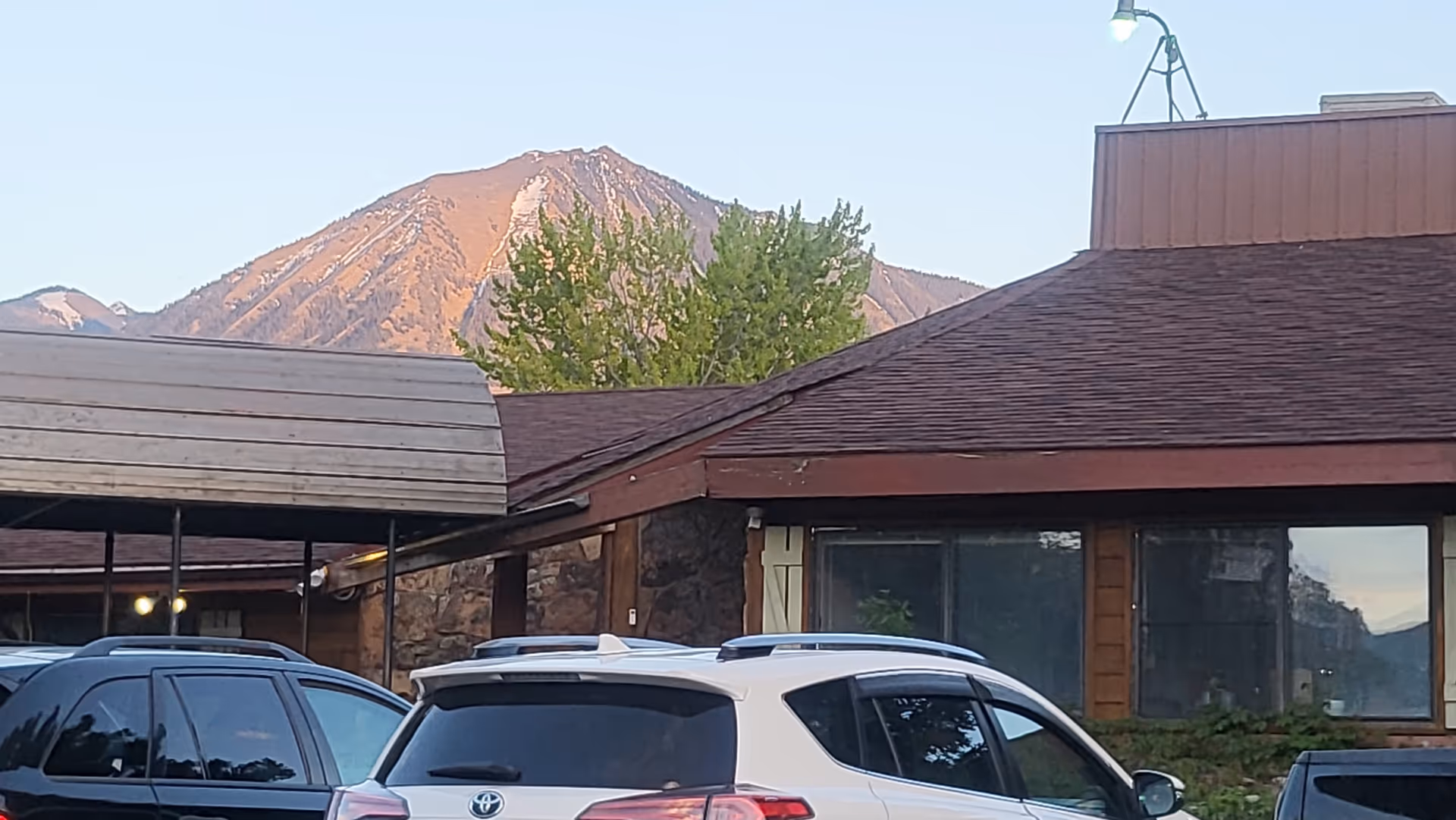Exterior view of Paonia Care and Rehabilitation Center with parked cars and mountains behind.