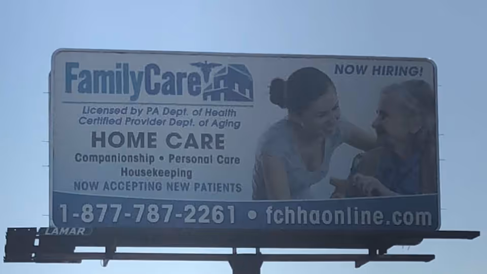 Outdoor billboard for FamilyCare Home Health Agency with contact number and Now Hiring notice.