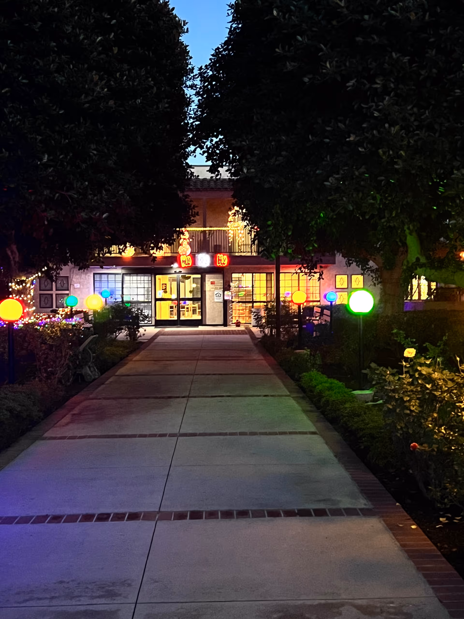 Night exterior of Canyon Terrace Senior Living with a lit walkway to the entrance.
