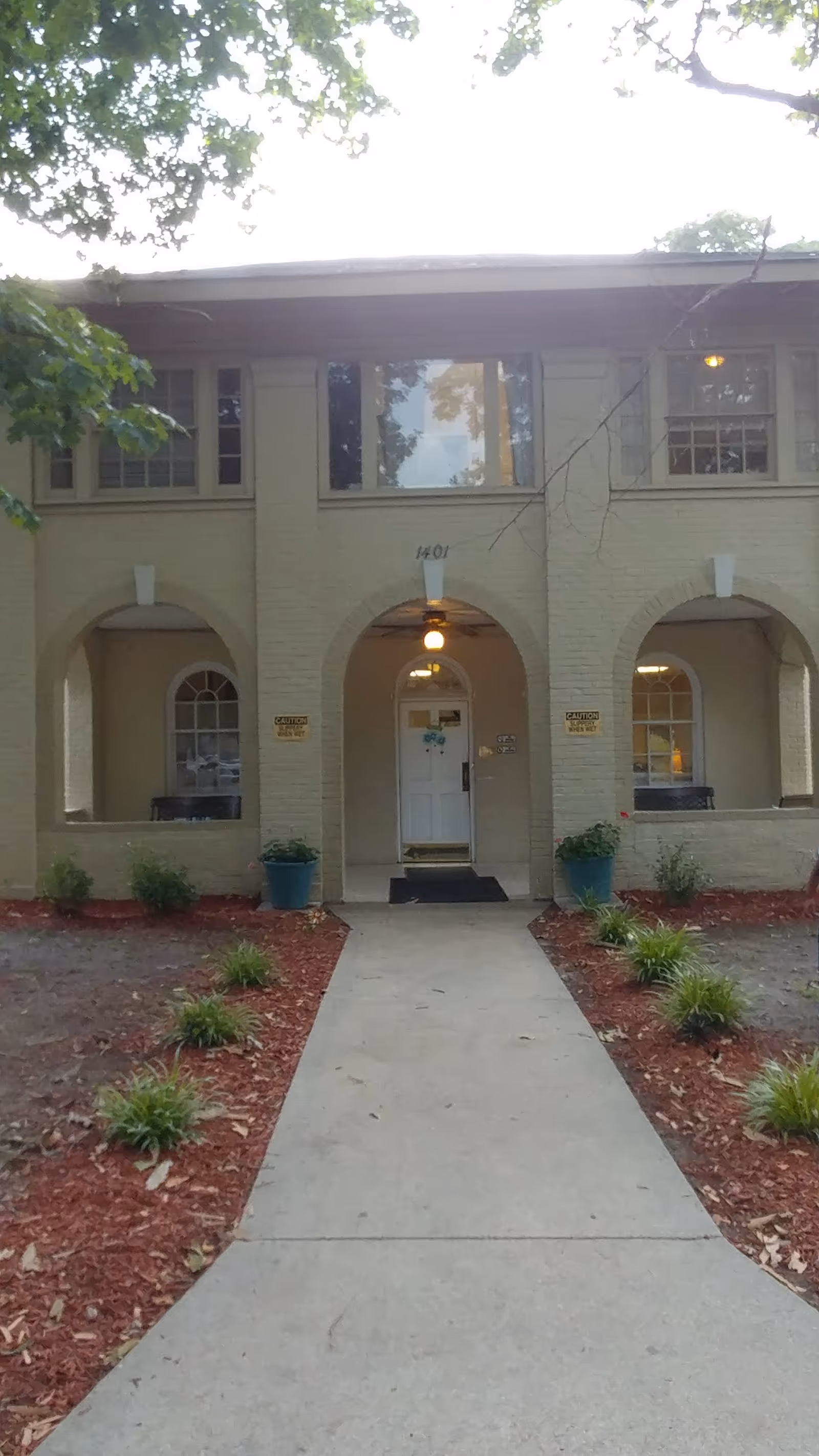 Two-story Magnolia Place entrance with arched doorway, walkway, and landscaped front yard.