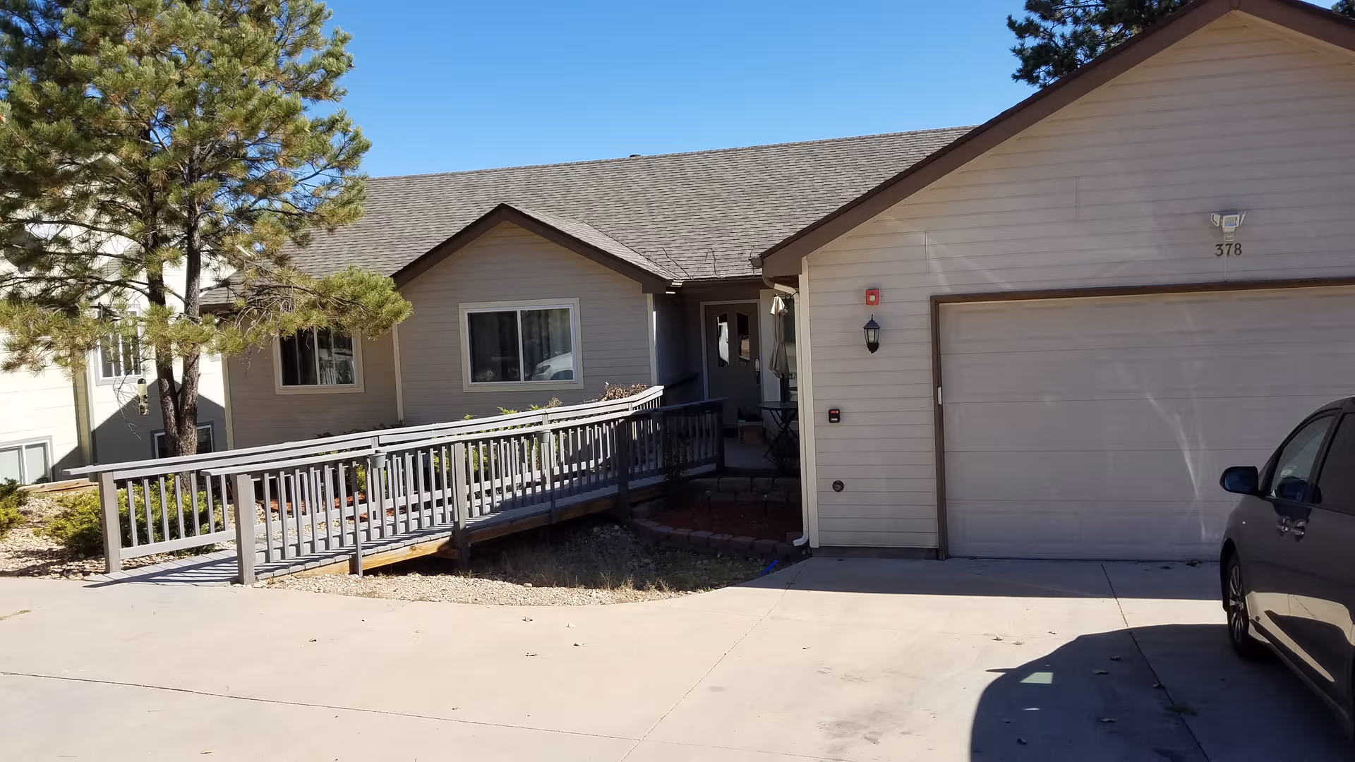 Front exterior of Pine Ridge Terrace Assisted Living with a ramp to entrance and parked car.