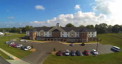 Front view of Windsor Estates Assisted Living, a brick-and-white facility with multiple entrances and parking.