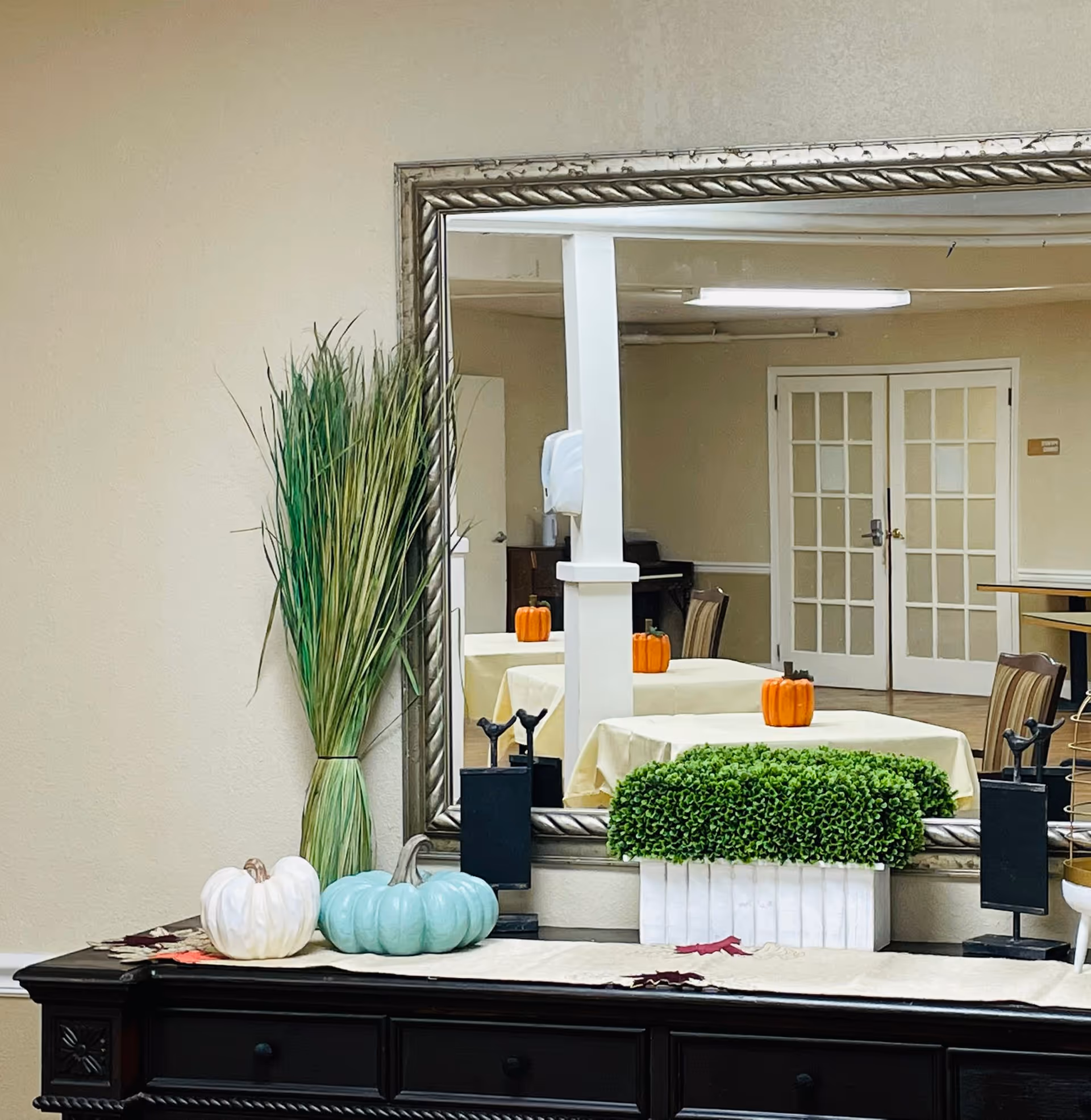 Interior facility lobby featuring autumn pumpkins, greenery, and a large framed mirror.