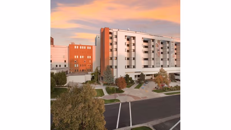 Exterior view of a multi-story medical facility with a red brick section and landscaping.