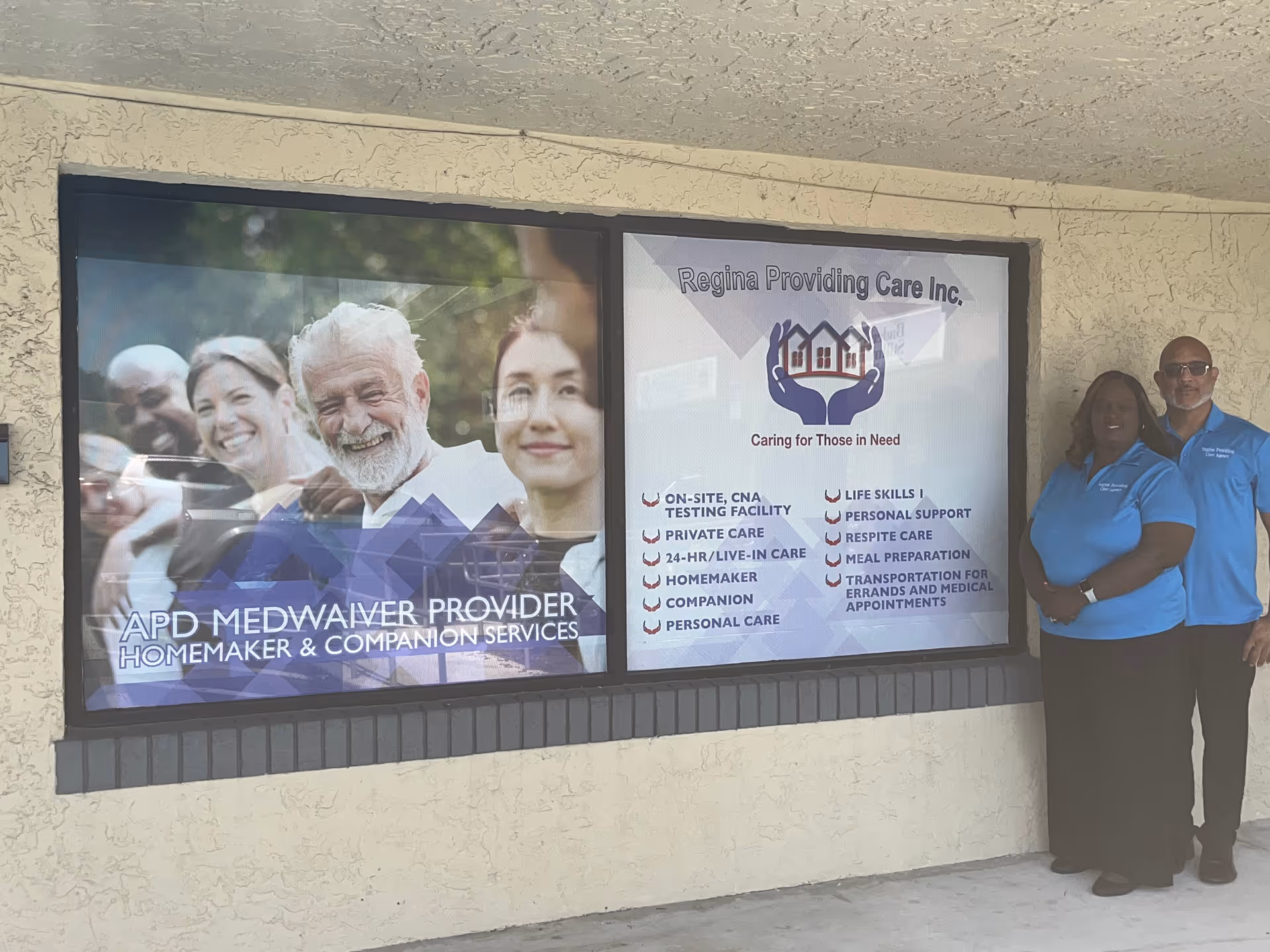 Outside view of Regina Providing Care Inc. with two staff members beside the front signage.