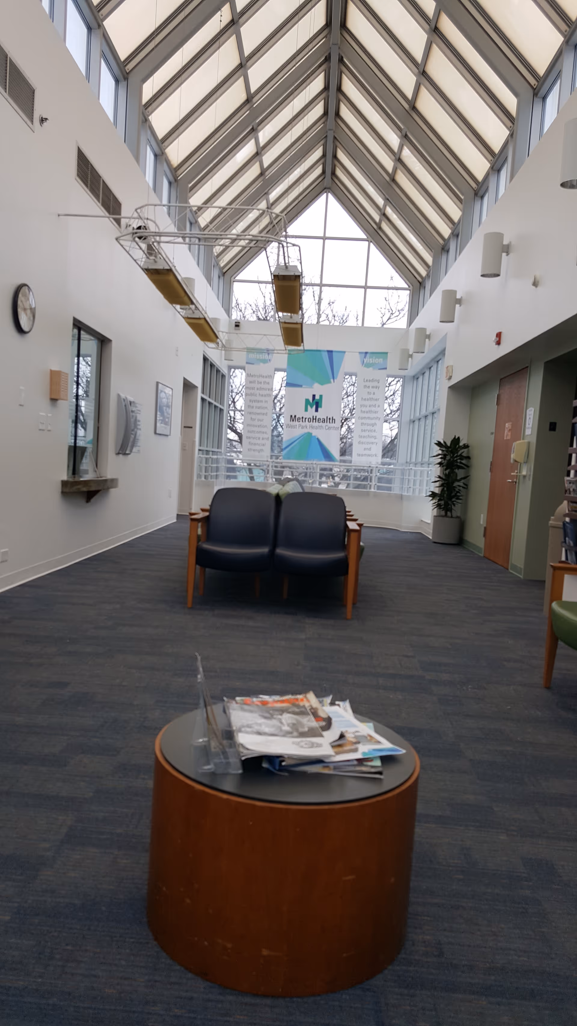 Bright indoor hallway with skylight roof, seating, and a MetroHealth banner.