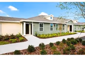 Single-story senior living facility with green siding, walkway, and landscaped front yard.