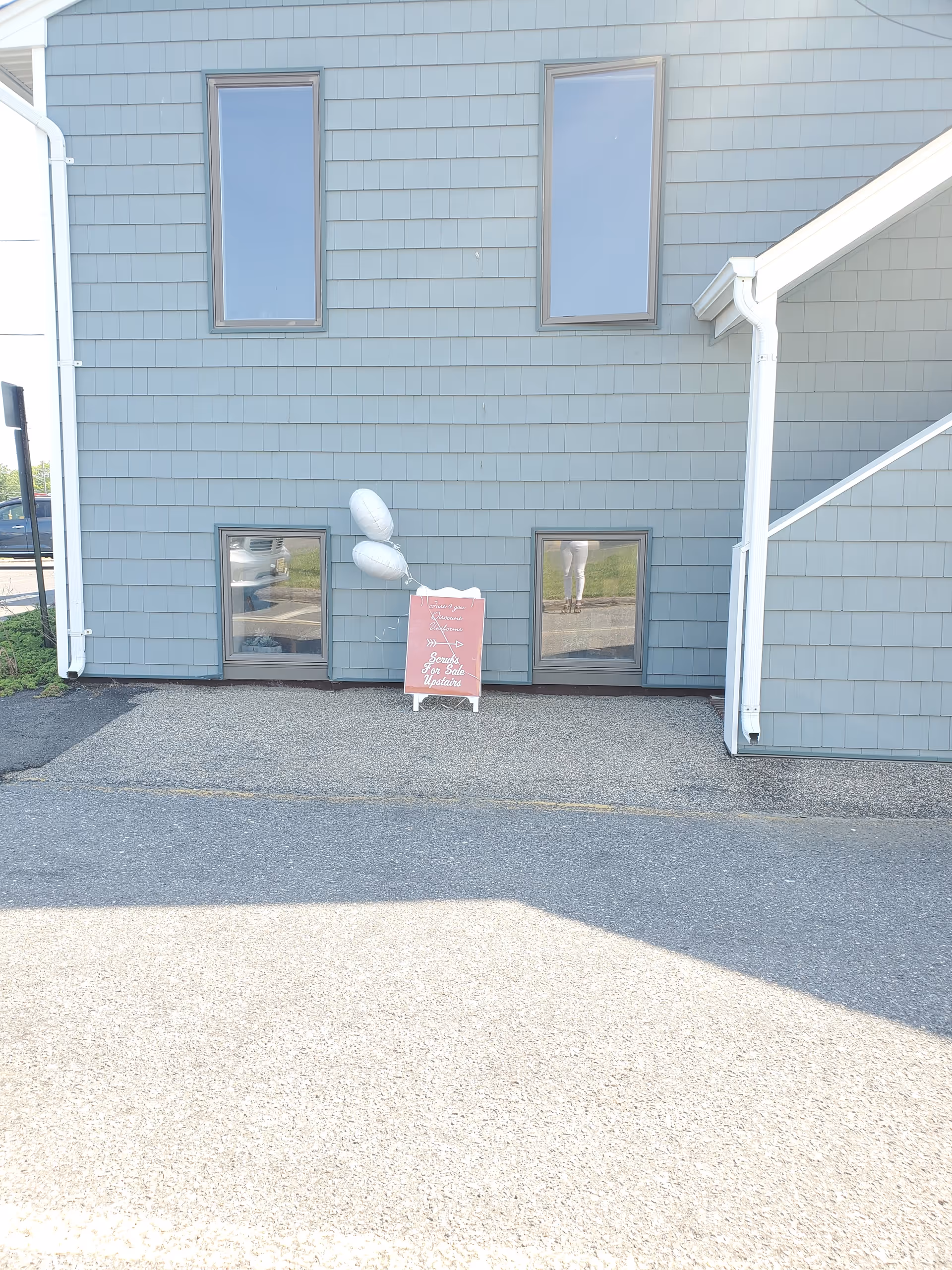Exterior view of a blue building with windows and a small sign with balloons.