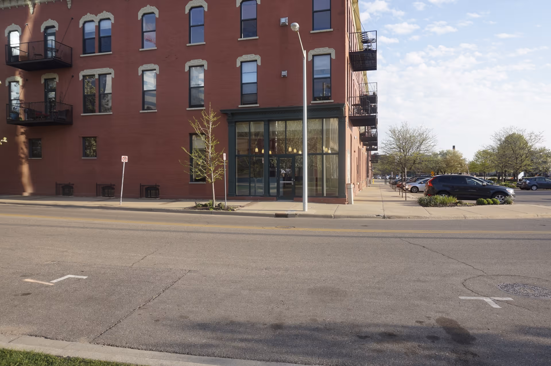 Exterior of a brick senior living building with glass entrance along a city street.