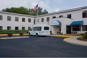Exterior view of Riverview Health & Rehab North with entrance, flagpole, and white van.
