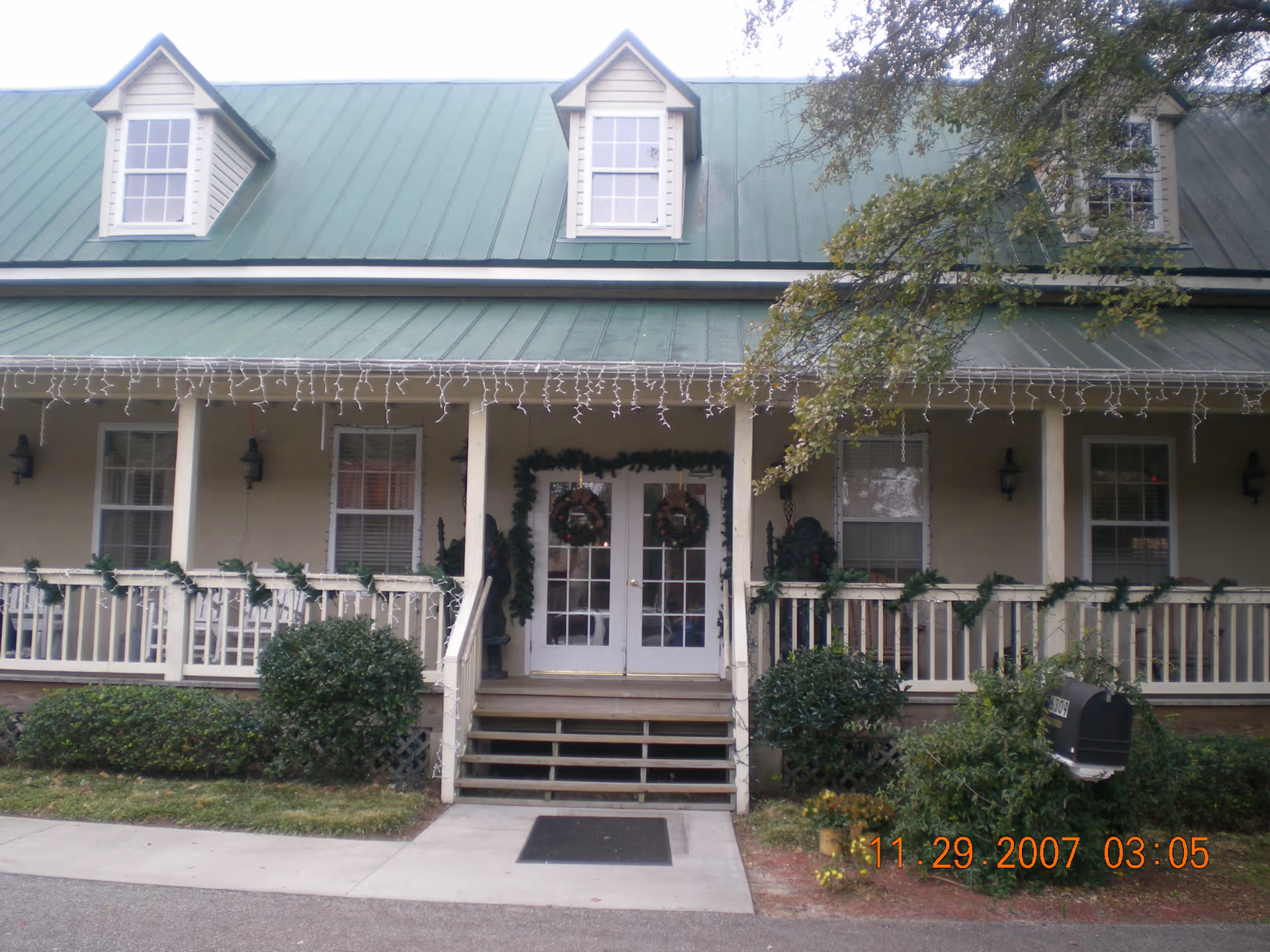 Front porch of Magnolias of Myrtle Beach with wreaths and string lights.