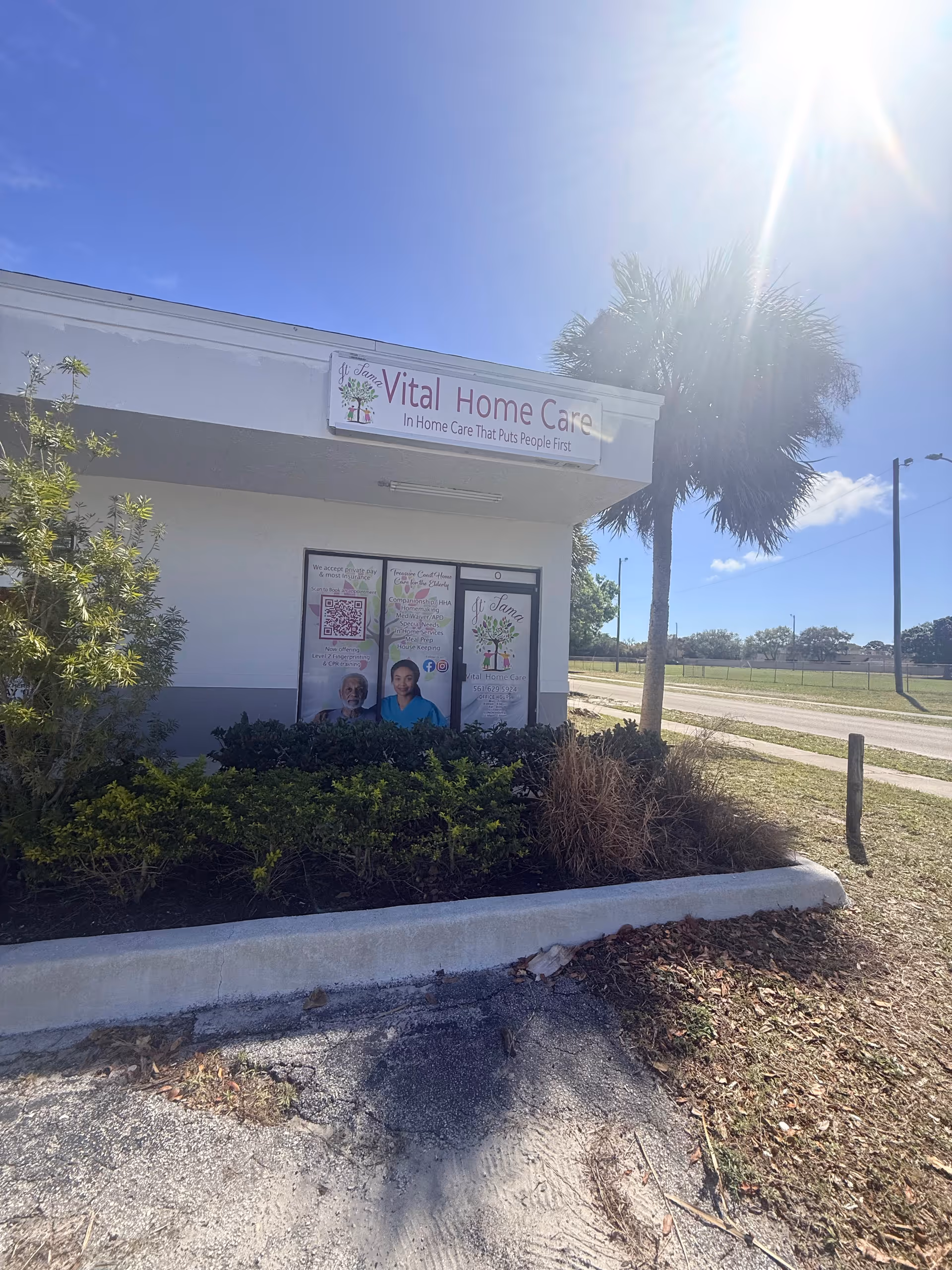 Front exterior of JT'TAMA Vital Home Care Inc building with sign and palm tree.