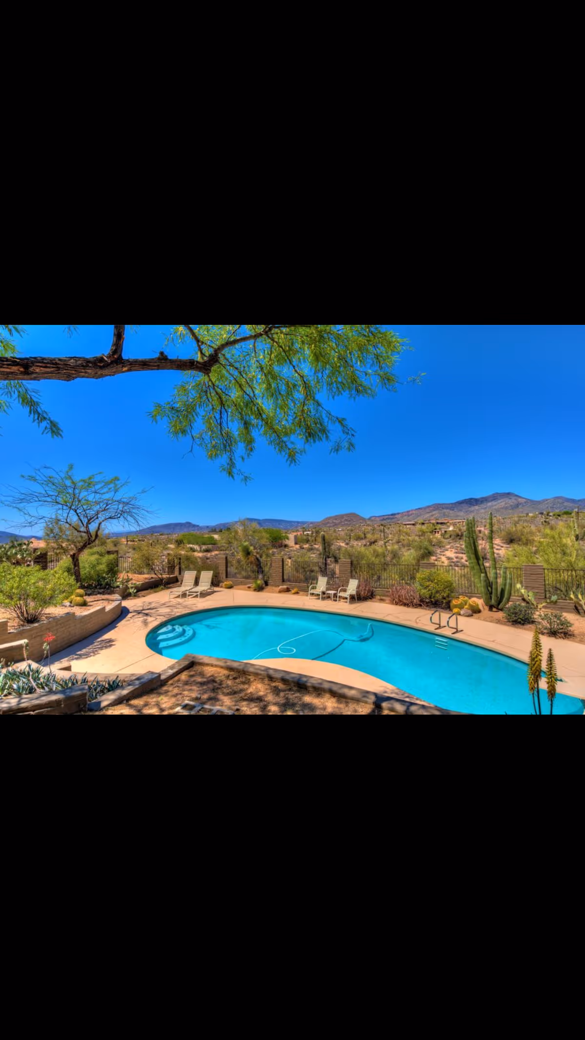 Sunny outdoor pool area with lounge chairs and desert landscape.