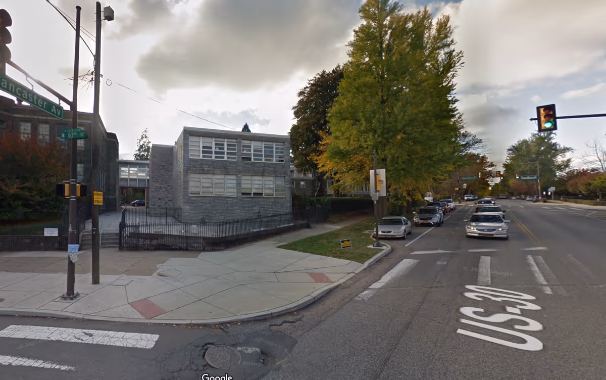 Exterior view of a brick senior facility beside a busy intersection with cars.