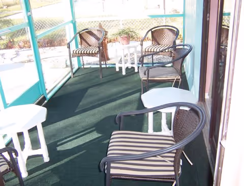 Enclosed outdoor seating area with wicker chairs and small white tables.
