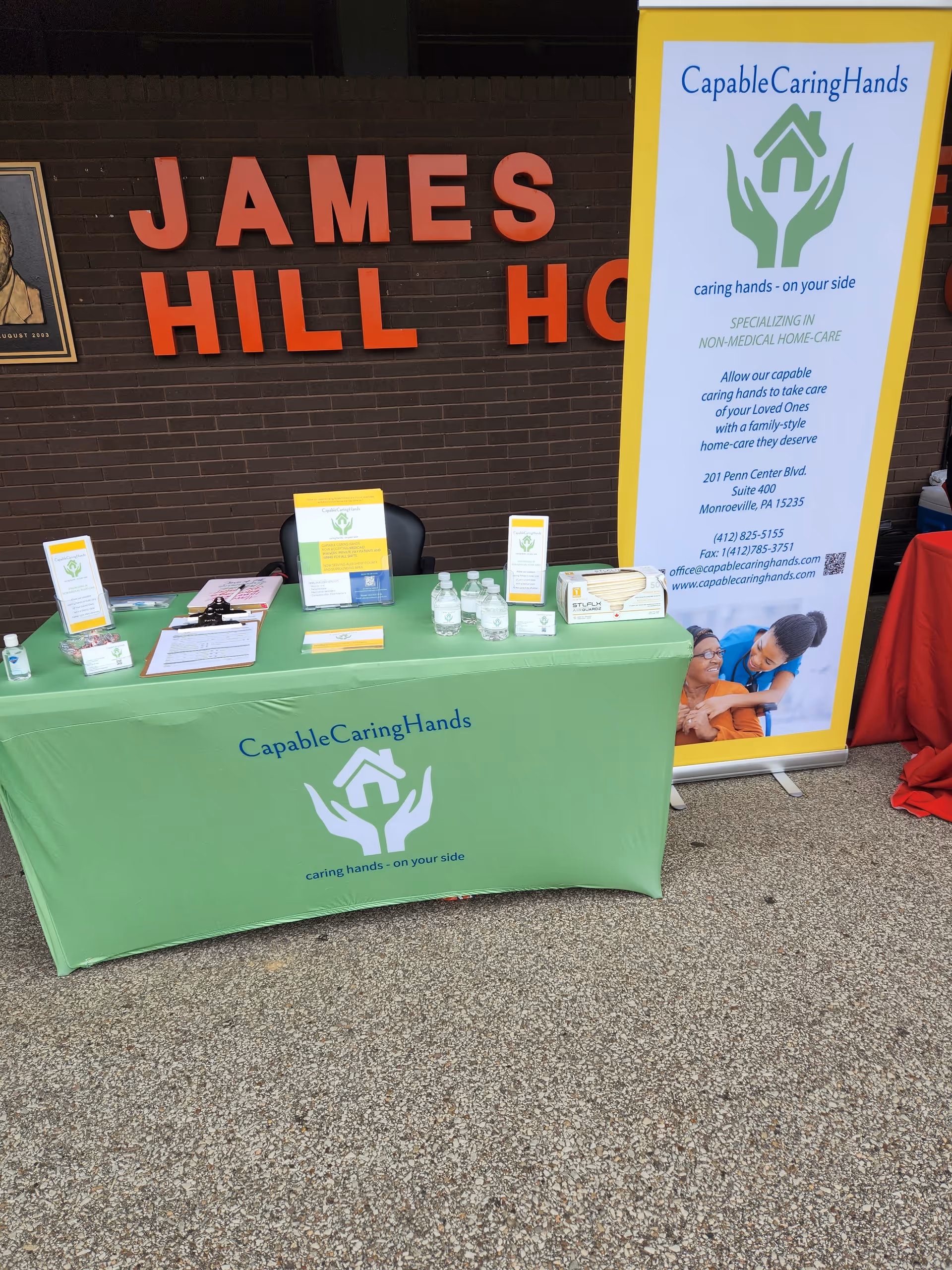 Promotional table for Capable Caring Hands in a lobby with a tall yellow banner.