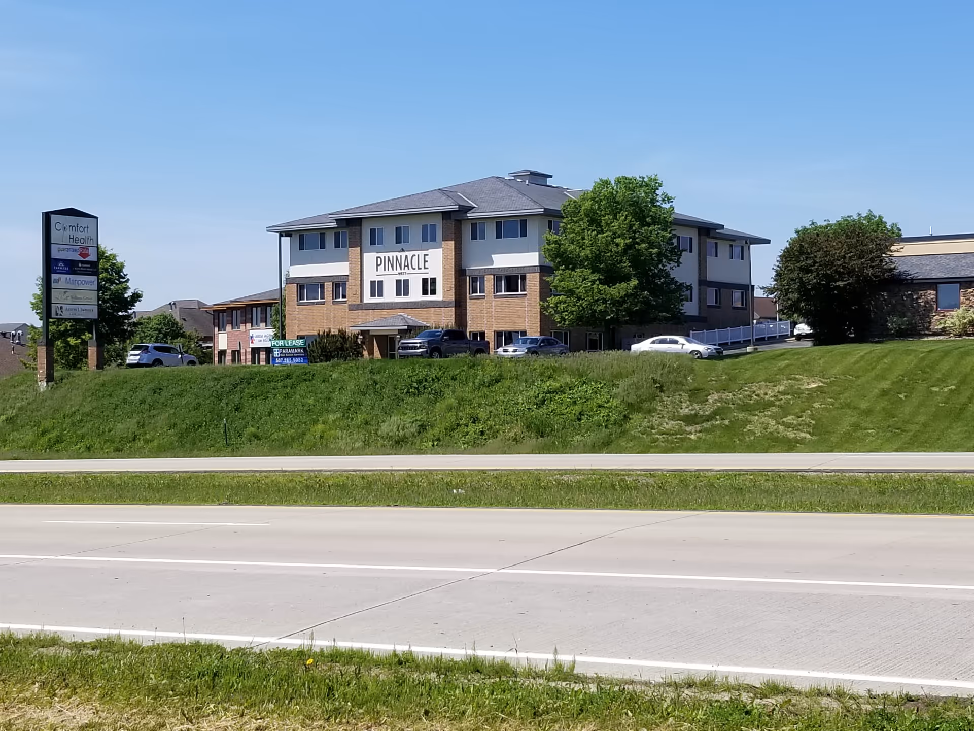 Exterior view of Comfort Health building with grassy embankment and parking lot.
