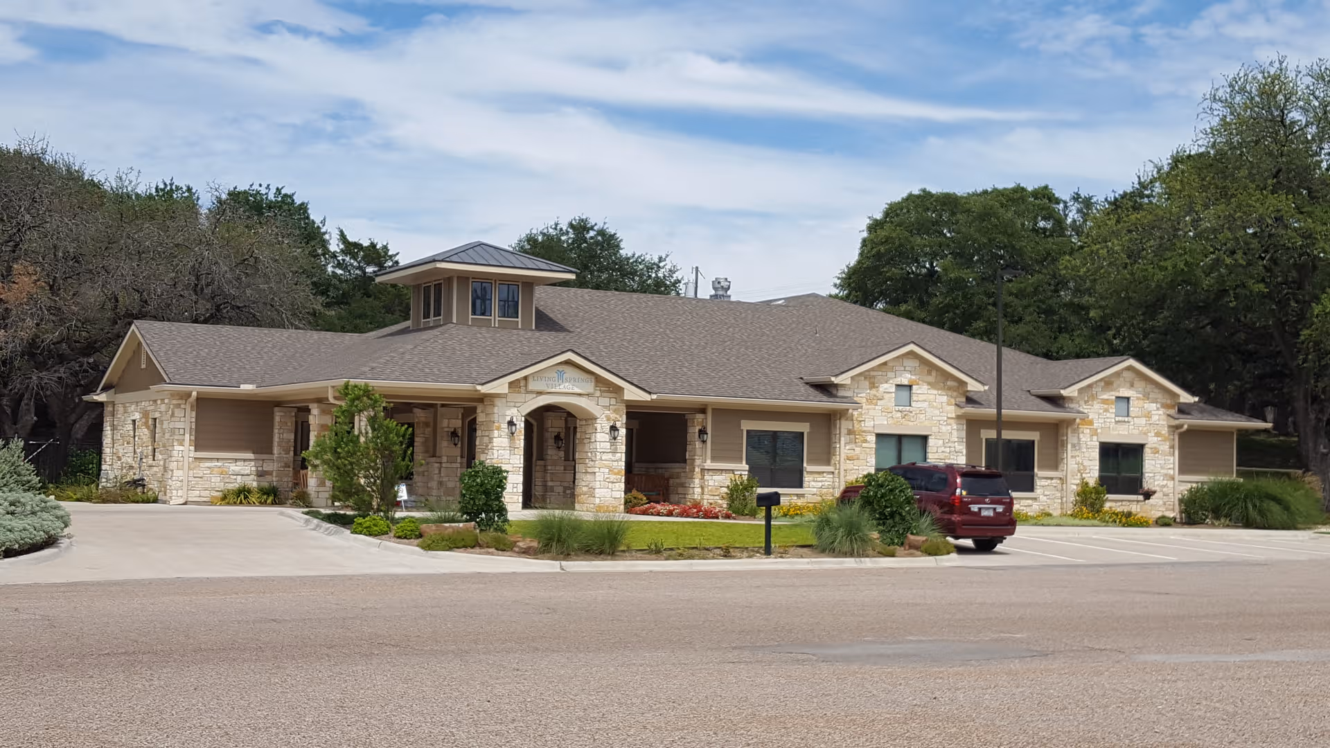 Stone building exterior of a senior living facility with parking and landscaping.