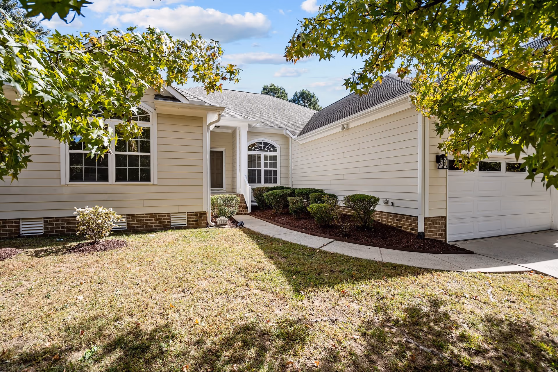 Front exterior of Miss Bell's Assisted Living with curved walkway, shrubs, and a two-car garage.