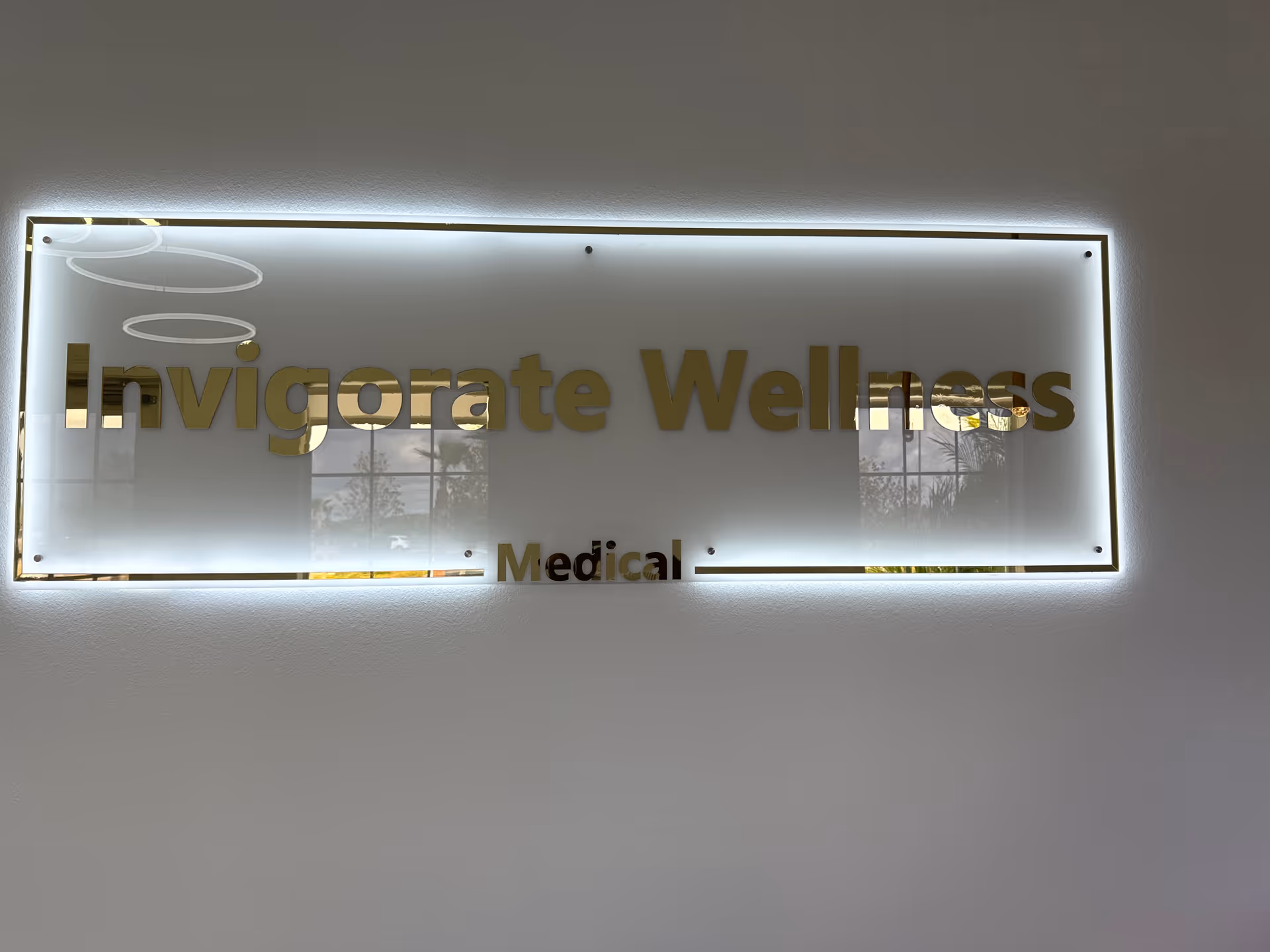 Backlit frosted wall sign reads Invigorate Wellness Medical in gold letters.